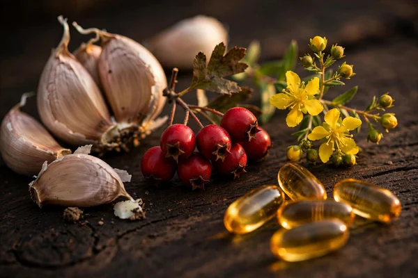 Ingrediente și suplimente naturale pentru inimă: căței de usturoi, bobițe de păducel, sunătoare și capsule de ulei de pește pe lemn